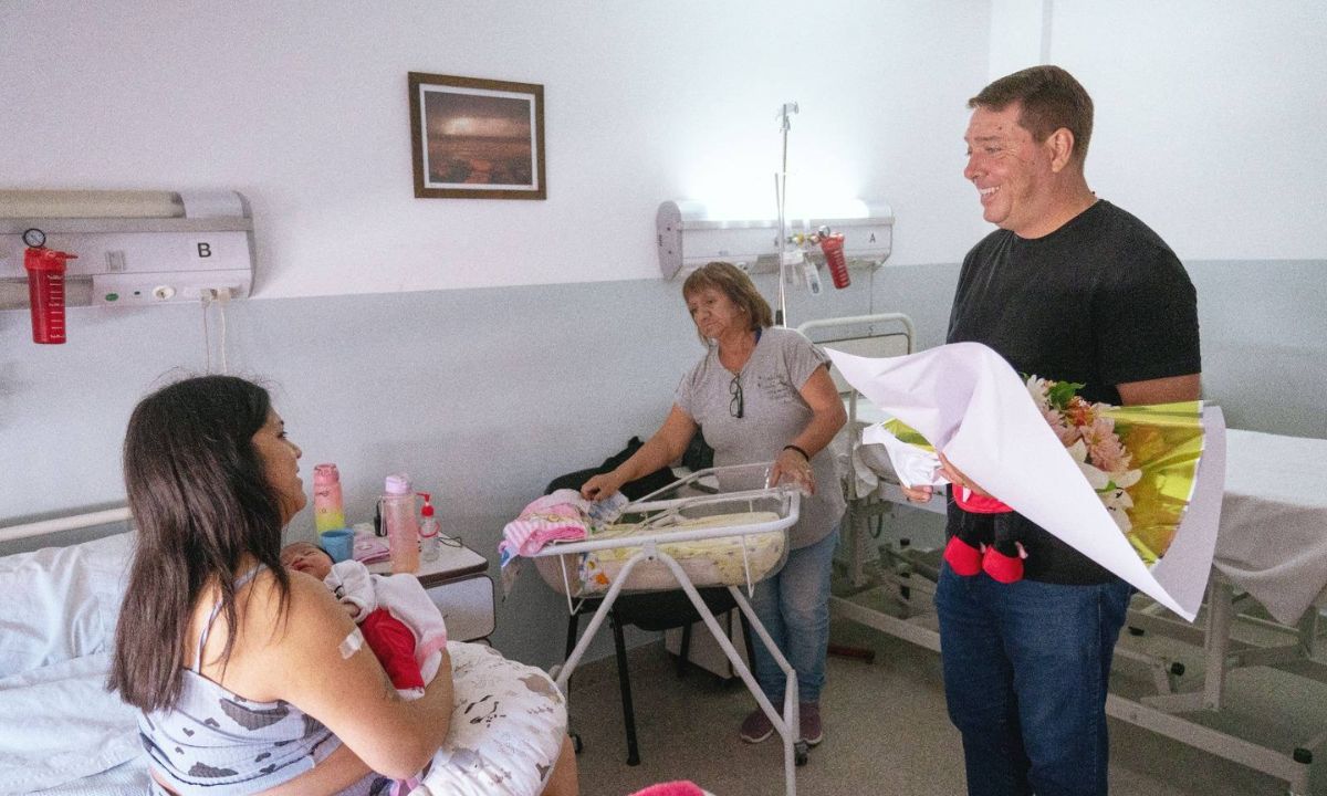 DAMIAN BISS con un ramo de flores para la mamá que sostiene a la bebé en brazos